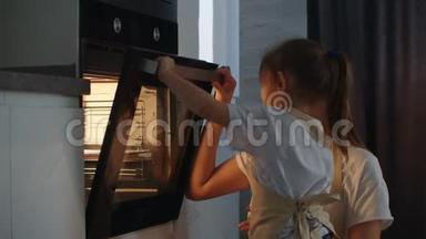 一个小女孩在厨房帮她妈妈，关上烤箱门。 妈妈幼儿园助理。 快乐的孩子